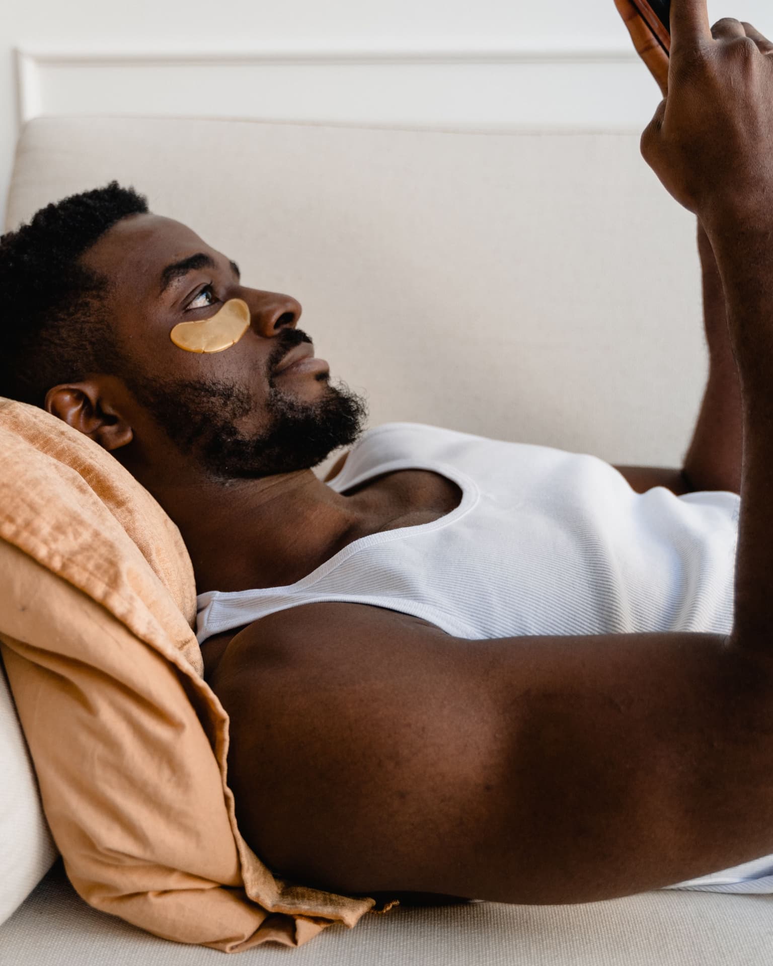 Man relaxing with gold hydrogel under-eye patches